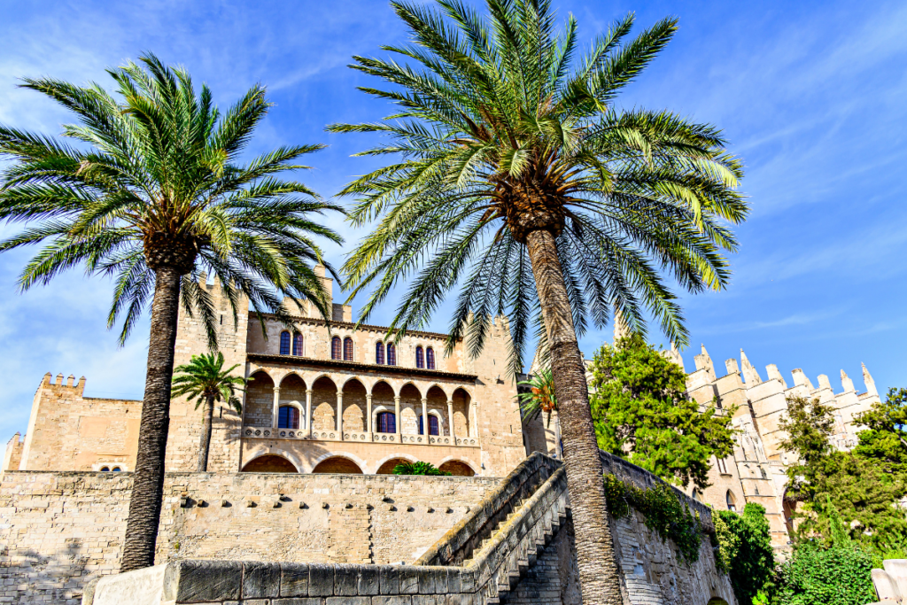 Palace of Almudaina Mallorca Spain with palm trees and historic stone architecture